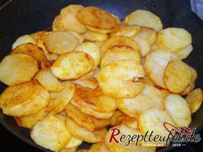 Die Bratkartoffeln werden gewürzt