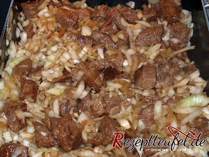 Die Zwiebeln zum Fleisch hinzufügen