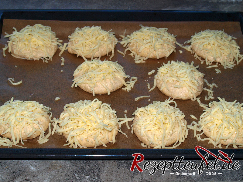 Flachgedrückte Teigkugeln mit geriebenem Käse bestreuen