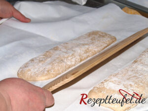 Jetzt das Tuch mit der linken Hand schwungvoll hochziehen und den Teigstreifen auf einen Handschießer kippen