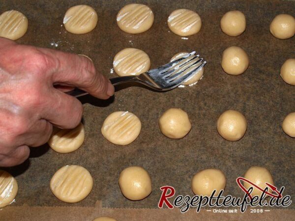 Mit einer Gabel werden die Teigkugeln flach gedrückt